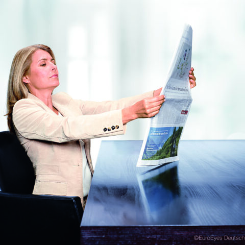 Frau mit Alterssichtigkeit liest Zeitung