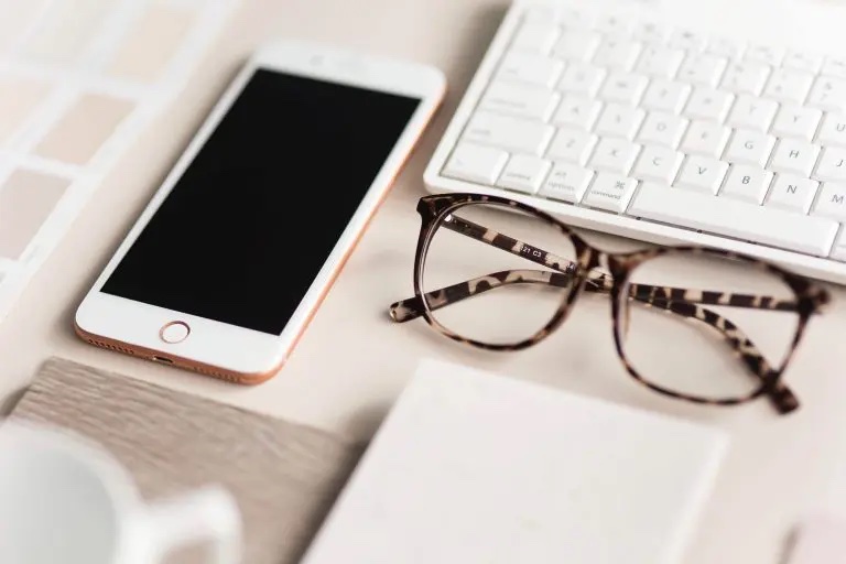 Smartphone und Brille auf Schreibtisch