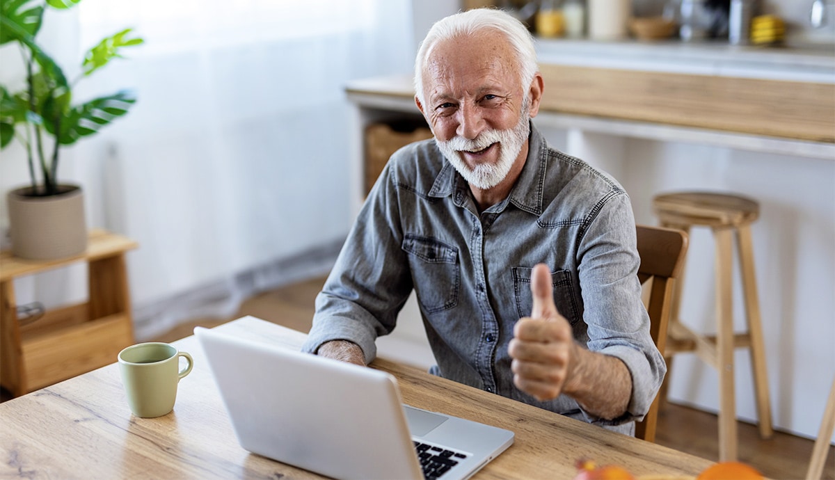 Zufriedener aelterer Herr am Laptop ohne Brille