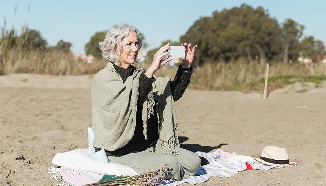 elderly woman taking photos on beach